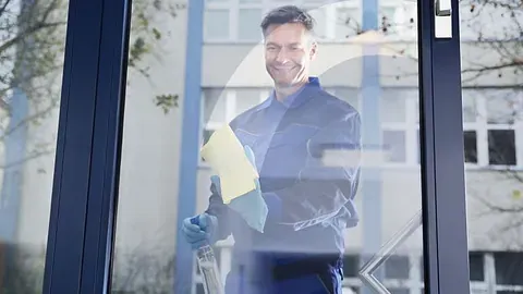 Renholdsarbeider på utsiden av glass med klut