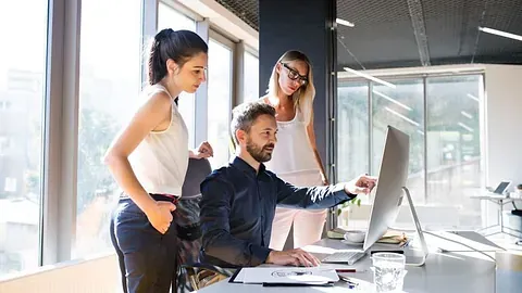 Én mann og to kvinner fokusert på dataskjerm